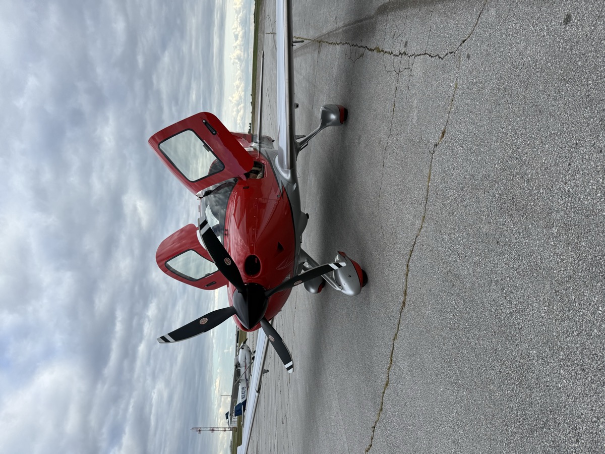 Red Cirrus aircraft with the doors open on the ramp